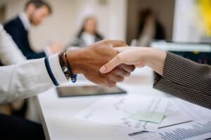 Diverse business professionals exchanging handshake in an office environment, symbolizing agreement.